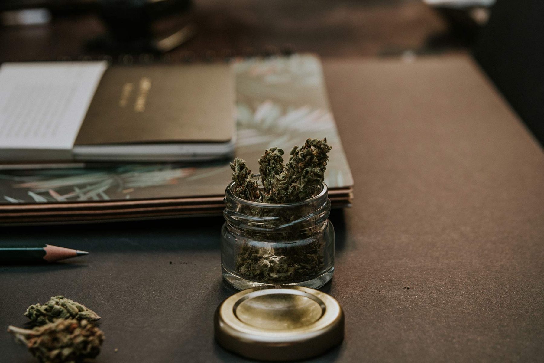Jar filled with cannabis placed by notebooks